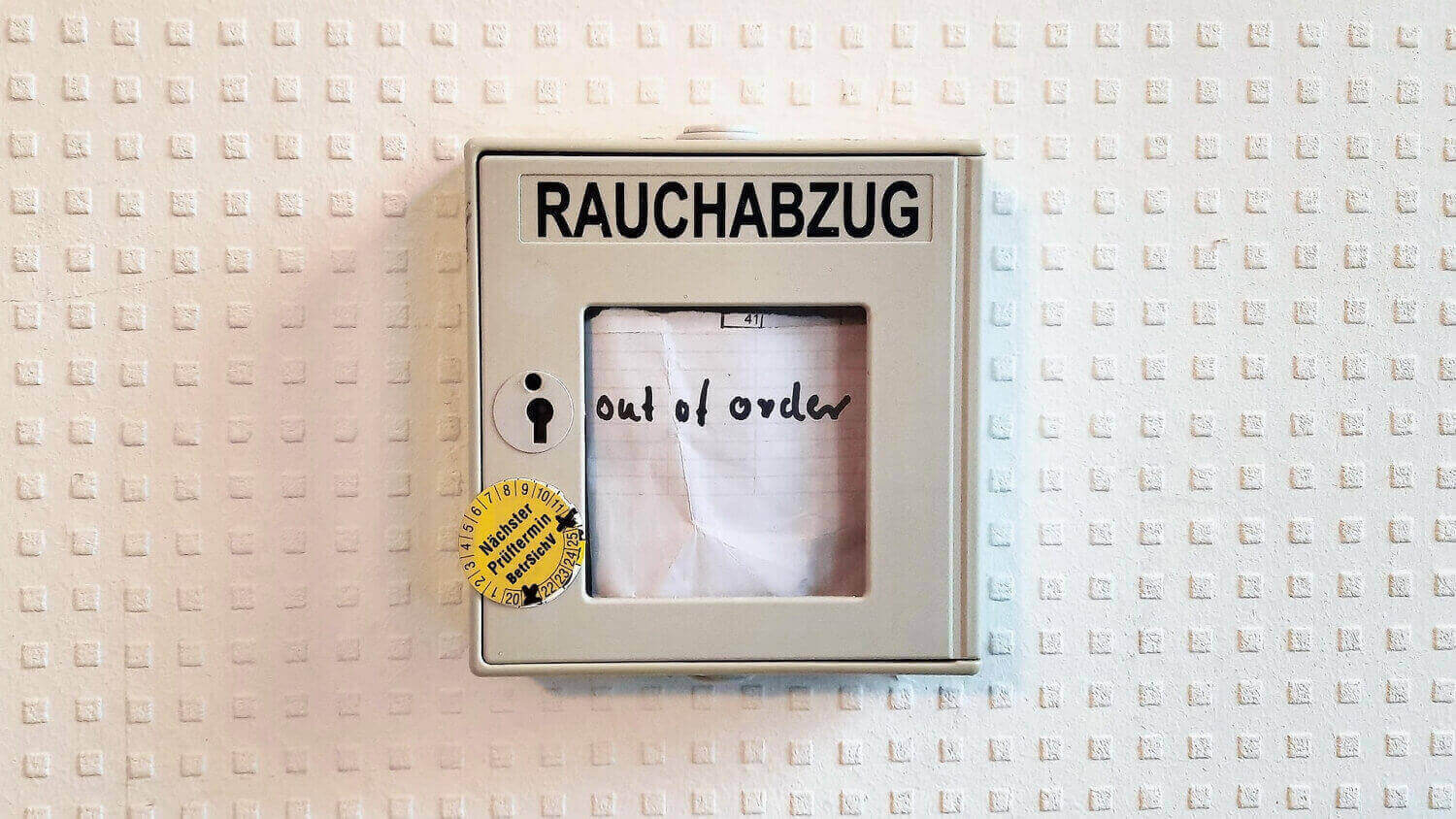A handwritten "out of order" note in a German smoke outlet control.
