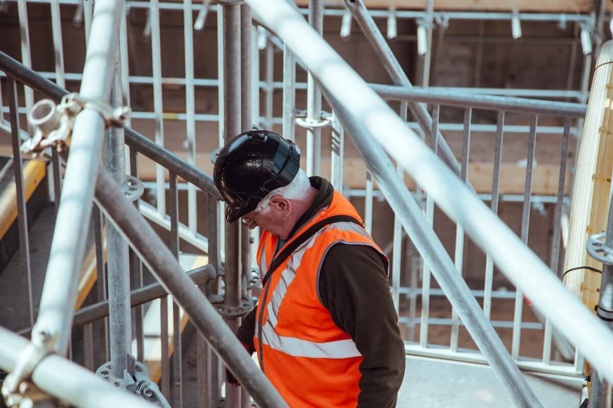 Worker in orange west with black helmet on staircase