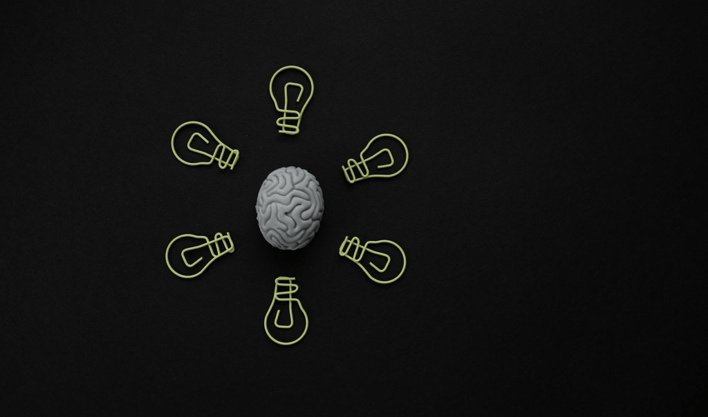 Brain on the black background surrounded by drawn light bulbs