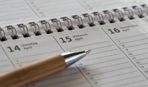 A close-up of an open planner showing dates in April, with a pen resting on the page near Wednesday the 15th.