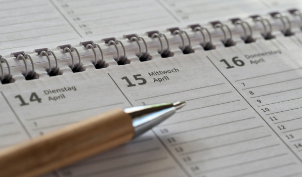 A close-up of an open planner showing dates in April, with a pen resting on the page near Wednesday the 15th.